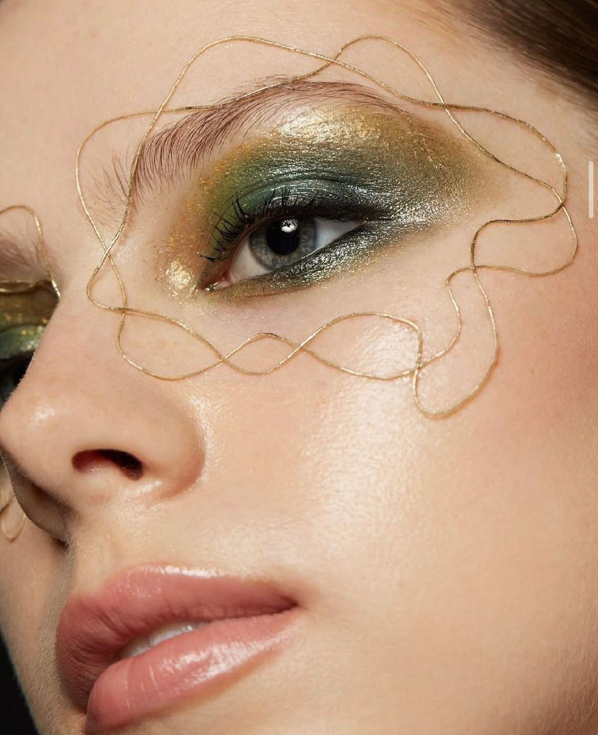 Editorial eye with green-gold shadow and gold wire art